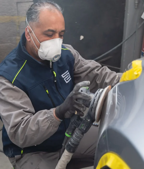 Un addetto SENESI rifinisce con cura la carrozzeria di un'auto prima della riparazione, garantendo un risultato impeccabile.
